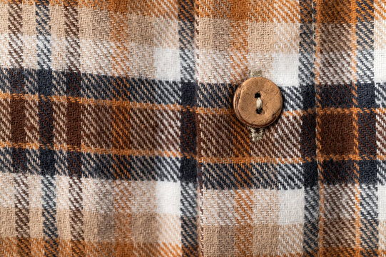 Close-up of details of plaid flannel fall shirt. Buttons, collar, sleeves, cotton plaid fabric in brown, red, beige tones. Fashionable, stylish clothing concept, texture of cozy fabric.