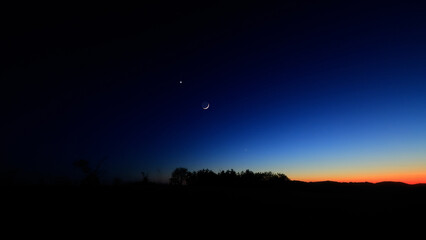 Moon on a twilight sky with stars, planets and landscape mountain silhouettes. © astrosystem