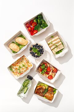 Daily diet nutrition food delivery set with salmon chicken rice salad rolls and detox water on white background