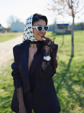 Smiling Asian woman in black blazer headscarf sunglasses portrait