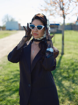 Asian woman in black blazer adjusting white sunglasses portrait