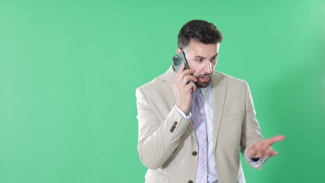  Adult man stands against green screen, holding smartphone to ear and having conversation 