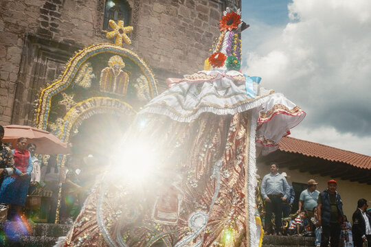San Lorenzo, Mexico - 10 August 2026: View of a traditional Danza de los Moros dancer in an elaborate, ornate costume standing before the decorated entrance of a stone church.