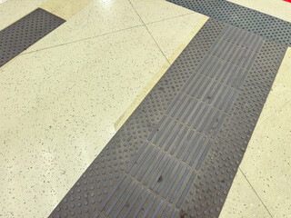 Fototapeta premium Close view of floor textures in a public space showing tiles and matting with tactile indicators