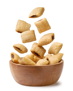Cereal pads falling in a wooden bowl on a white. Isolated