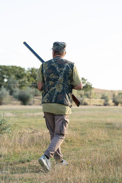A hunter with a gun in camouflage clothing. A gentleman with a gun, medium shot, unrecognizable.