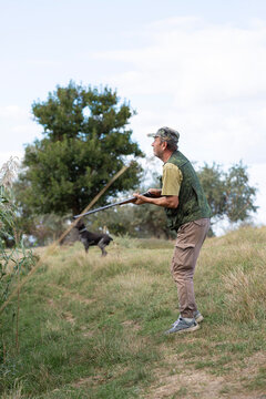 An adult hunter hunts in the autumn countryside. He fires a shotgun.