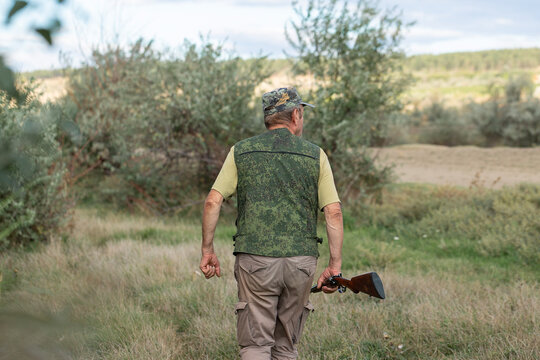 A hunter with a gun in camouflage clothing. A gentleman with a gun, medium shot, unrecognizable.