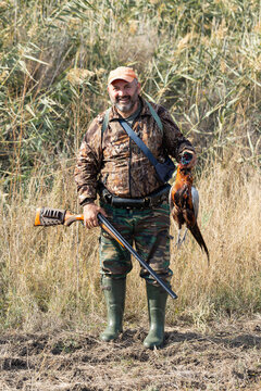 A hunter holds a pheasant in his hands. A successful hunt, a trophy game.