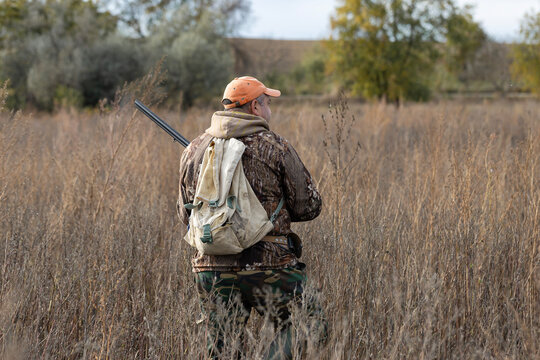 A hunter with a gun in camouflage clothing. A gentleman with a gun, medium shot, unrecognizable.
