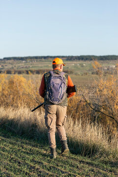 A hunter with a gun in camouflage clothing. A gentleman with a gun, medium shot, unrecognizable.