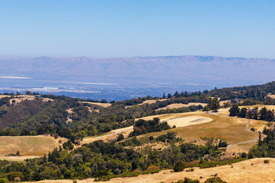 Elevated view over golden California hills towards distant hazy mountains and the San Francisco Bay