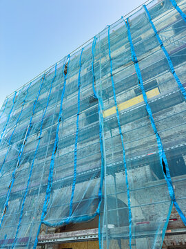 Construction progress on a building site with safety nets visible in a clear sky