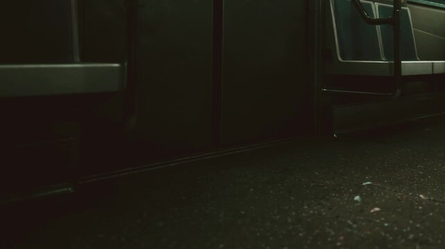 A subway train stands still with empty seats. The floor shows indications of use. Evening light creates a shadowy atmosphere in the train.