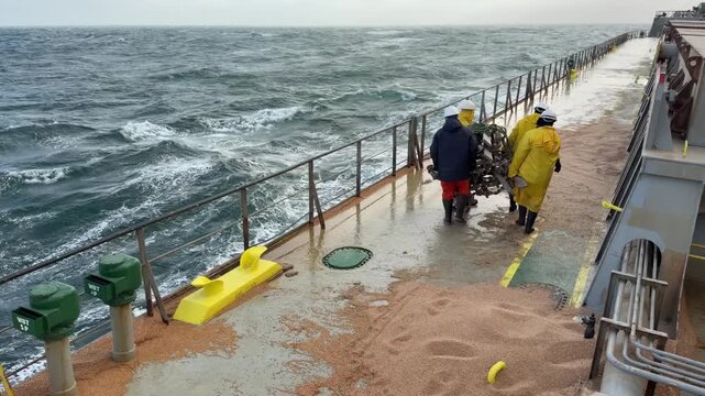 sea passage of ship. crew team working on deck. remove pilot ladder due to bad weather condition.