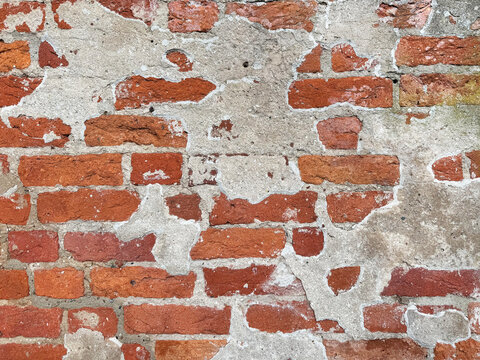 Old red brick wall texture with peeling plaster