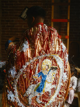 Angahuan, Mexico - 24 July 2026: View of a person wearing an ornate, sequined red cape featuring an embroidered depiction of Saint James on horseback, part of the traditional Moros y Cristianos dance.