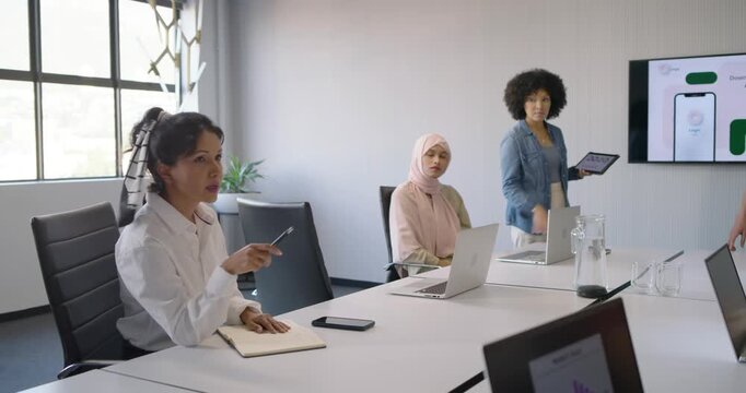 Diverse female team Indian woman leading, reviewing and gesturing in room with tablet, copy space