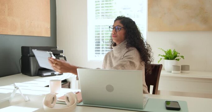 Adult African American woman at home laptop seeing tablet bringing it closer to read, sipping mug