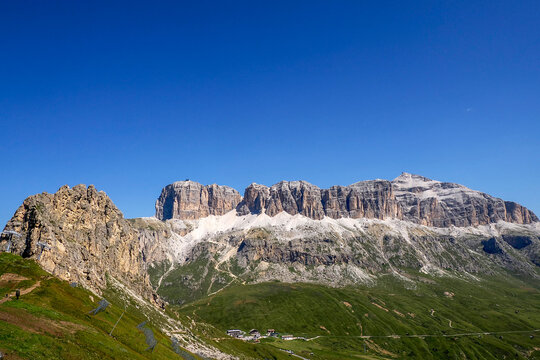 Pordoi massif in the Dolomites rocky cliffs, as seen from the high-altitude green meadows near the famous Viel dal Pan Trail.