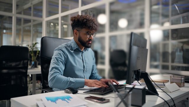 Hindu business man computer chatting with client project developing Arabian businessman using modern technology desktop ethnic guy working in office male executive work documents diagram on table