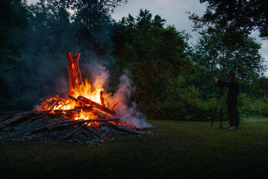 View of a large bonfire at night with a photographer capturing the scene on a tripod in Vormsi, Laane County, Estonia.