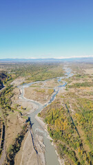 High angle aerial drone view of winding mountain river bed flowing through countryside valley with autumn trees and clear blue sky in Georgia stock photo © moryachka