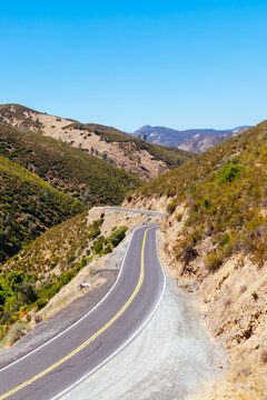 Winding paved highway curves through arid mountain canyon in rural Mariposa County California