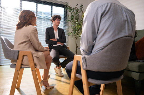 Therapist leading a group discussion as participants listen, share experiences,