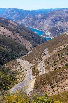 Winding mountain road descending into a valley with lake and mountains in California