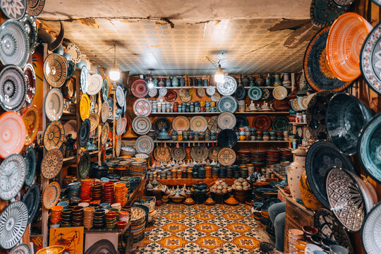 Marrakesh, Morocco - 25 November 2023: View of a traditional pottery shop in the Marrakesh souks, filled with colorful handmade ceramic plates, bowls, and tajines displayed on shelves and walls.