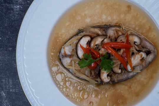 Steamed king mackerel with plum sauce, ginger, and shiitake mushrooms in a white dish, Top view.