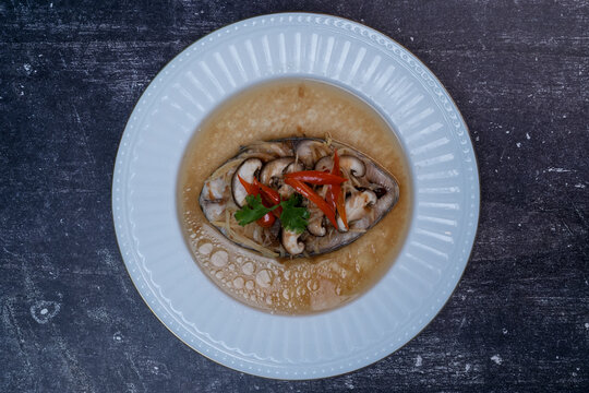 Steamed king mackerel with plum sauce, ginger, and shiitake mushrooms in a white dish, Top view.