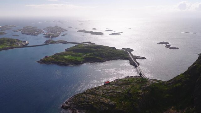 An aerial panorama captures bridges connecting rocky islets toward the fishing village of Henningsvaer under daylight in the Lofoten archipelago in Norway.