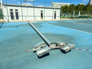 Construction work is ongoing on a sports court area with equipment placed near the building on a sunny day