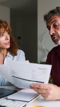 Mature couple reviewing bills and financial documents at home