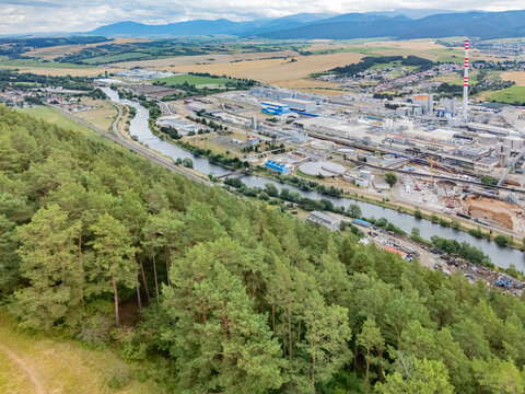 Aerial view of the Mondi SCP factory complex situated along the Vah river, surrounded by dense pine forests and agricultural fields in Ruzomberok, Zilinsky kraj, Slovakia.