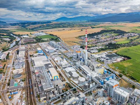 Aerial view of the Mondi SCP factory featuring industrial buildings, a tall chimney, railway tracks, and surrounding fields in Ruzomberok, Zilinsky kraj, Slovakia.