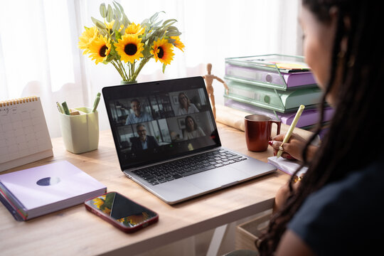African American woman takes notes during a video call