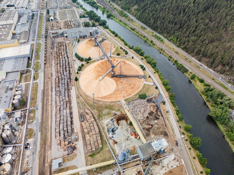 Aerial view of the Mondi SCP factory featuring large wood chip piles, conveyor systems, and industrial infrastructure situated along a river in Ruzomberok, Zilinsky kraj, Slovakia.
