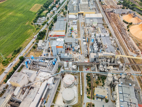 Aerial view of the Mondi SCP factory complex with large storage tanks, wood chip piles, industrial buildings, and railway tracks in Ruzomberok, Zilinsky kraj, Slovakia.