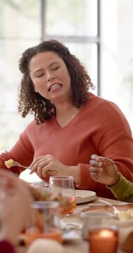 Vertical video: African American mom at meal cutting with fork and sharing food, laughing at table
