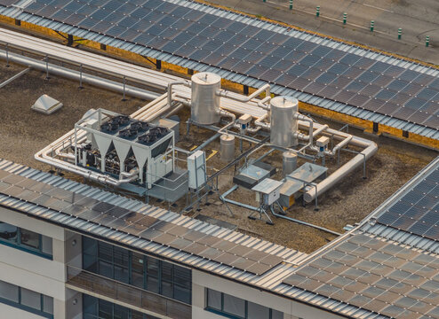 Aerial view of rooftop HVAC and cooling infrastructure surrounded by photovoltaic solar panels, showing renewable energy integration in Valence, Auvergne-Rhone-Alpes, France.