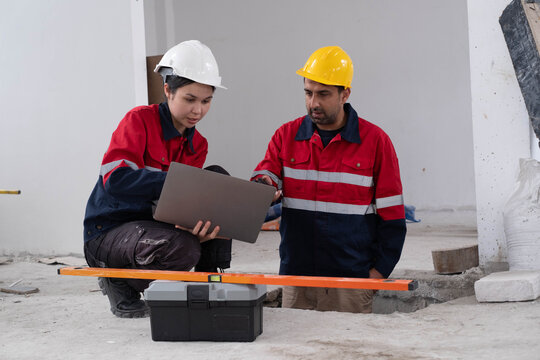 Construction engineer reviewing project data on a laptop with a technician at an indoor building site. Safety inspection, teamwork, digital documentation, renovation planning and quality control.