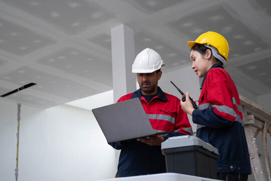 Construction engineers managing site operations with a laptop and two-way radio in building project, highlighting teamwork, engineering, project coordination, workplace safety, and quality inspection.
