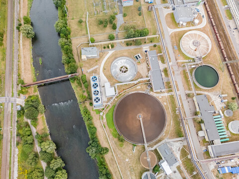 Aerial view of the Mondi SCP factory featuring large circular water treatment tanks, industrial infrastructure, and a river flowing alongside railway tracks in Ruzomberok, Zilinsky kraj, Slovakia.