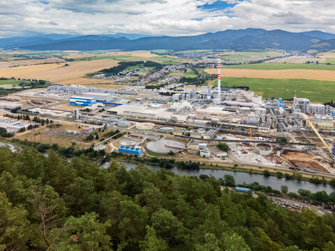 Aerial view of the Mondi SCP factory complex with a tall smokestack, industrial buildings, and water treatment facilities near a river and mountains in Ruzomberok, Zilinsky kraj, Slovakia.