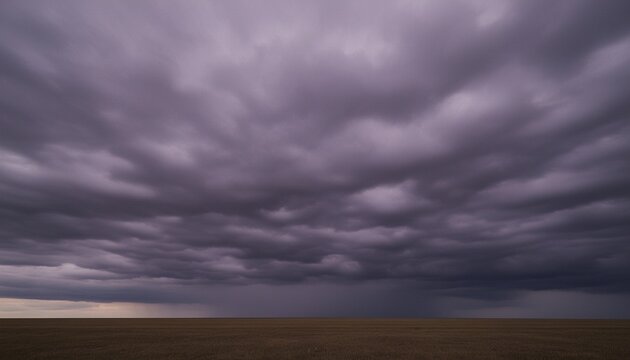 Layers of grey and purple stratus clouds move rapidly across a flat ominous horizon