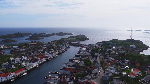 An aerial flight over the coastal fishing village and harbor of Henningsvaer in Lofoten, Norway, opening out toward the ocean and outer islets.