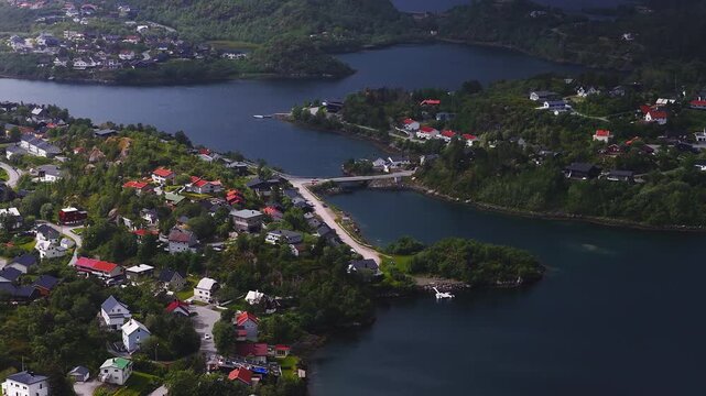 Aerial view of a coastal Norwegian settlement with residential houses, roads, and bridges along the blue waters and islands in Lofoten, Norway.
